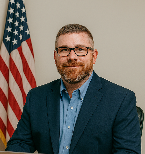 Jeff Fortune sitting at computer in front of a USA flag